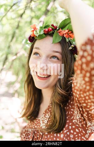 Eine Frau mit einer Blumenkrone, die einen Baumzweig ergreift Stockfoto