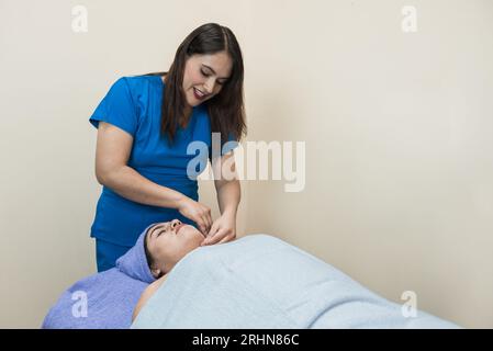 Junge lateinerin, die einer Frau ein Gesicht macht. Stockfoto