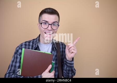 Kaukasischer junger gutaussehender lächelnder Student in Brillen zeigt seinen Finger zur Seite Stockfoto