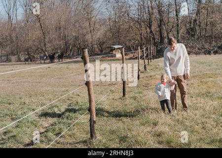 Ein Mann hält ein kleines Kind an der Hand und geht über das Feld Stockfoto