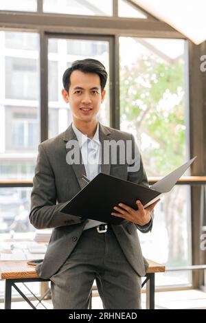 Junger asiatischer Geschäftsmann, der im Büro und in der mobilen Akte arbeitet Stockfoto