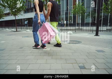Das junge Paar geht Hand in Hand auf dem Bürgersteig entlang Stockfoto