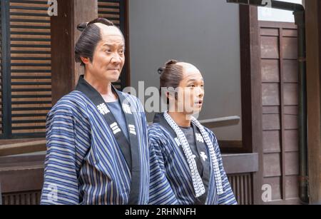 Zwei Männer, die in historischen Kostümen gekleidet sind, machen eine Ankündigung in einem Yukata in einem Comedy-Stück aus der edo-Zeit im Edomura Wonderland. Stockfoto