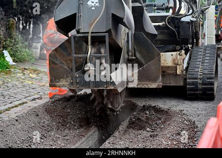 Grabenfräse (Bobcat) zum Schneiden von Kanälen durch Pflaster in der Straße zum Verlegen von Entenarbeit für Glasfaserkabel, Großbritannien Stockfoto