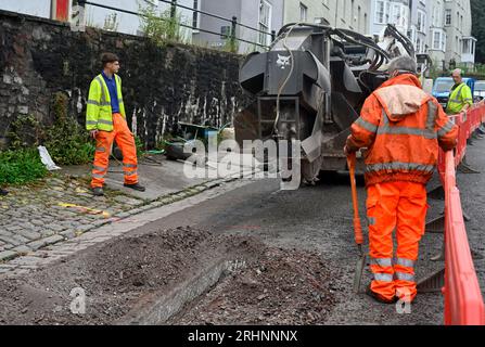 Grabenfräse (Bobcat) zum Schneiden von Kanälen durch Pflaster in der Straße zum Verlegen von Entenarbeit für Glasfaserkabel, Großbritannien Stockfoto