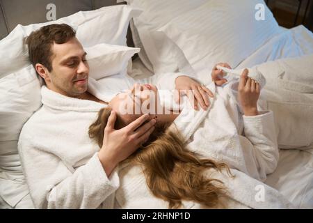 Liebender Mann, der die Haare seiner schönen Frau streichelt, die auf seiner Brust liegt, Stockfoto