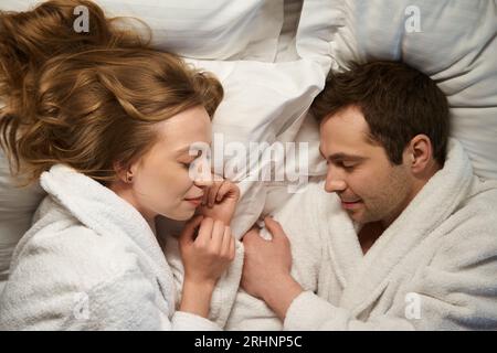 Wunderschönes Paar, das nach dem Spa in warmen Bademänteln eingeschlafen ist Stockfoto