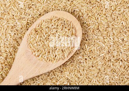 Flache Lage Nahaufnahme von köstlichem und gesundem braunem Reis mit Holzlöffel und Kopierraum Stockfoto