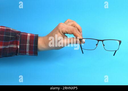 Schwarze Kunststoffgläser mit Handhalterung, isoliert auf blauem Hintergrund. Foto mit hoher Auflösung. Volle Schärfentiefe. Stockfoto