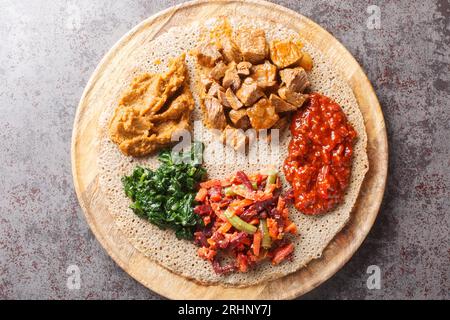 Injera ist ein Sauerteigfladenbrot aus Teffmehl, das mit Füllung aus nächster Nähe auf dem Holzbrett auf dem Tisch serviert wird. Horizontale Draufsicht von oben Stockfoto