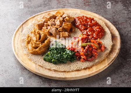 Injera ist ein Sauerteigfladenbrot aus Teffmehl, das mit Füllung aus nächster Nähe auf dem Holzbrett auf dem Tisch serviert wird. Horizontal Stockfoto