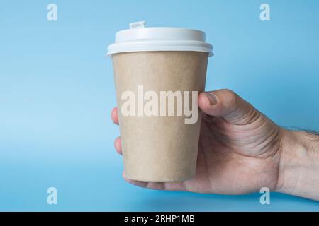 Papiertasse Kaffee in der Hand des Mannes. Pappbecher für Heißgetränk. Idee für Layout isoliert auf Farbhintergrund, Flesh Farbe, freien Raum für Text Stockfoto