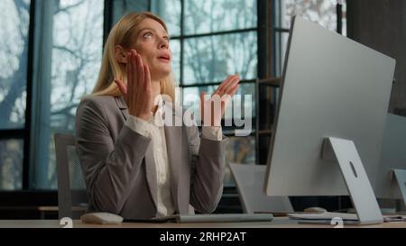 Die kaukasische Frau der 40er Jahre streckt sich die Hände in der Luft glücklich mit dem Ende der Computer-Arbeit Geschäftsfrau beendet Online-Job im Büro Arbeit erleichtert zufrieden. Weiblich Stockfoto