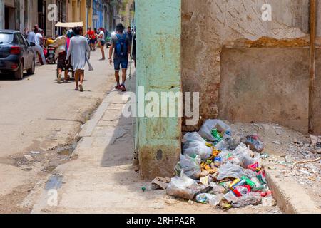 Havanna, Kuba - 27. Juli 2023: Die Leute gehen an einem Müllhaufen auf dem Bürgersteig vorbei Stockfoto