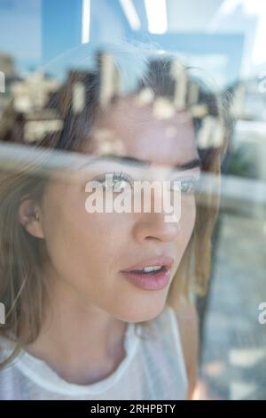 Die Frau schaut aus dem Fenster Stockfoto