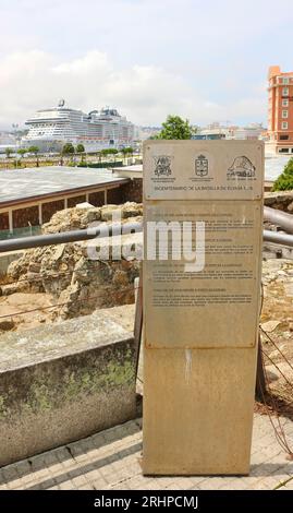 Blick auf die Landschaft mit einem Touristeninformationsschild an der alten Stadtmauer und dem Kreuzfahrtschiff MSC Virtuosa in der Ferne im Hafen A Coruña Galicien Spanien Stockfoto