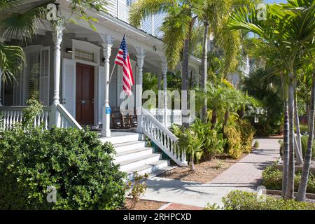 Key West, Florida, USA. Blick durch Palmen auf die hölzerne Veranda von Chelsea House, einem historischen gasthaus an der Truman Avenue, Altstadt. Stockfoto