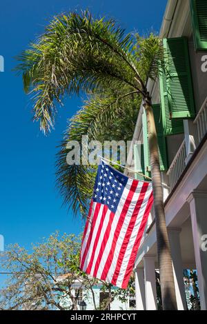 Key West, Florida, USA. US flag flying beneath palm tree from balcony of the Audubon House Museum, Old Town. Stock Photo