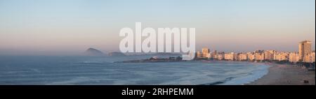 Rio de Janeiro, Brasilien: Skyline, Blick aus der Vogelperspektive im rosa Licht des Sonnenaufgangs des Copacabana Strandes, das Copacabana Fort und felsige Hügel voller Vegetation Stockfoto