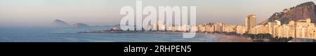 Rio de Janeiro, Brasilien: Skyline, Blick aus der Vogelperspektive im rosa Licht des Sonnenaufgangs des Copacabana Strandes, das Copacabana Fort und felsige Hügel voller Vegetation Stockfoto