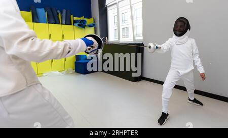 Porträt von zwei Fechtern vor dem Hintergrund einer Sportarena. Das Konzept des Zaunens. Duell. Gemischte Medien Stockfoto