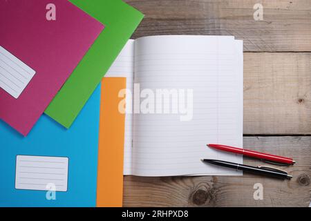 Bunte Schulbücher und zwei Kugelschreiber auf Holztisch, Blick von oben Stockfoto