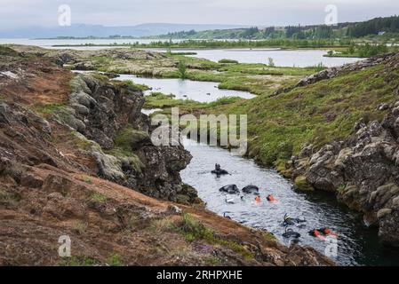 Südwest-Island im Frühsommer 2021, Schnorchler in Silfra Fissure, weltberühmter Tauchplatz. Eine kilometerlange Gletscherspalte im isländischen Pingvellir-Nationalpark, die in den Pingvallavatn mündet. Die Spalte entstand durch das Auseinanderdriften der nordamerikanischen und eurasischen Platte. Er wird jedes Jahr um etwa 7 mm erweitert. Stockfoto