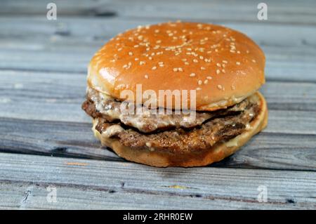 Doppelt saftiges, dickes Rinderpatty mit Käse, der mit Sauce bedeckt ist, Pilzen in einem großen Sesambrötchen, ein Hamburger-Sandwich mit Rindfleisch und spezieller Sauce Stockfoto