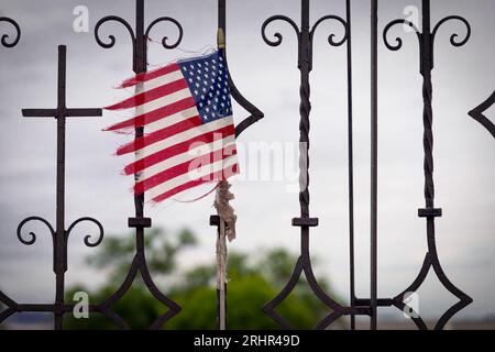 An einem Tor befestigt, weht eine zerrissene amerikanische Flagge in der Nähe von El Paso, Texas. Stockfoto