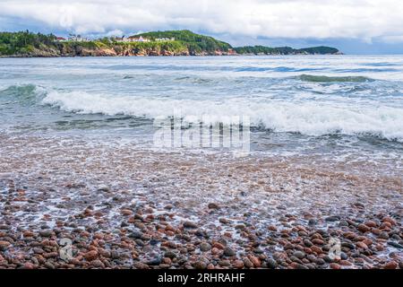 Wellen stürzen an Land in der wunderschönen Szene von Ingonish Beach Cape Breton Island. Keltic Lodge ist im Hintergrund zu sehen. Stockfoto