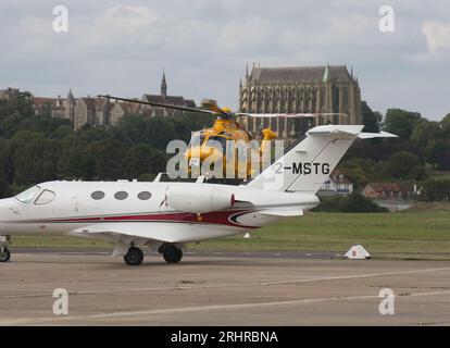 Ein AW-169-Rettungswagen des Kent Surrey Sussex Trust verlässt den Brighton City Airport mit einem Cessna 510 Citation Business Jet im Vordergrund. Stockfoto