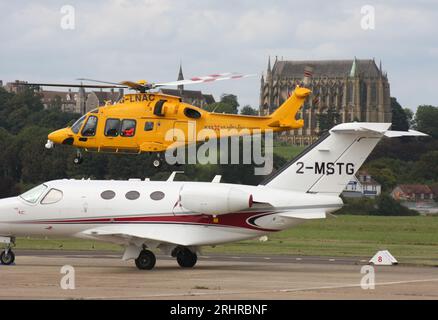 Ein AW-169-Rettungswagen des Kent Surrey Sussex Trust verlässt den Brighton City Airport mit einem Cessna 510 Citation Business Jet im Vordergrund. Stockfoto