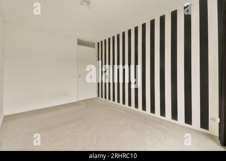 Ein leeres Zimmer mit schwarz-weiß gestreiften Tapeten an den Wänden, als ob niemand da wäre Stockfoto