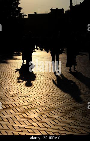 Tägliches Leben in Japan „Silhouetten von Menschen, die durch die Stadt spazieren, beleuchtet von der untergehenden Sonne“ Stockfoto