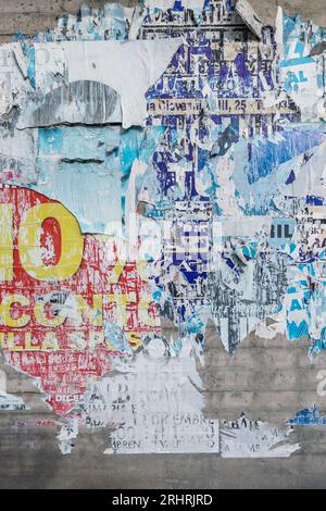 Betonwand mit bunten, zerrissenen Plakaten. Grunge-Hintergrund Stockfoto