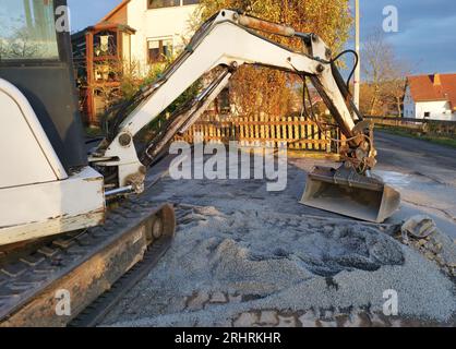 Baggerschaufel verteilt Pflastersteine zwischen neu verlegten Pflastersteinen Stockfoto