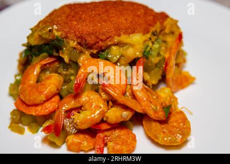 Typischer Acaraje – traditioneller brasilianischer Knödel aus Erbsen mit schwarzen Augen und Zwiebeln, gefüllt mit Vatapa, Caruru, Tomatensalat und Garnelen. Stockfoto