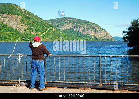 Ein erwachsener Mann wirft seine Krabbenfalle in den Hudson River in der Nähe von Cold Spring, New York Stockfoto