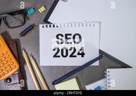 Auf der Lupe befinden sich Papierstreifen mit der Aufschrift SEO 2024. Stockfoto