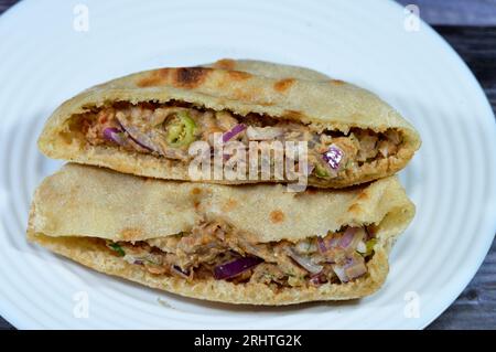 Ein flaches Brot mit pürierten Fava-Bohnen, gemischt mit Öl, Sesam-Tahini, Kreuzkümmel, Gewürzen, Scheiben Chilischeffer und Zwiebeln, selektiver Fokus auf traditionellen Pop Stockfoto