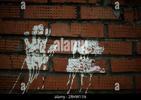 Handabdruckfarbe. Abdruck an der Ziegelwand. Weiße Silhouette der Handfläche. Fingerabdrücke an der Wand. Stockfoto