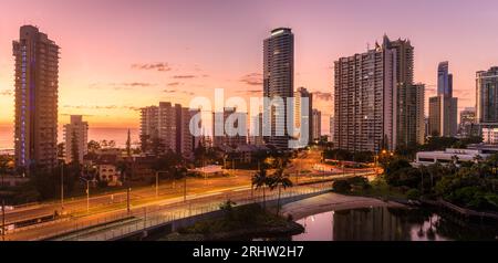 Ein spektakulärer Sonnenaufgang erleuchtet die Surfers Paradise Hochhauswohnungen mit schönem goldenen Licht. Grenzt an das Meer und die Kanalentwicklung. Stockfoto