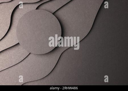 Kreis aus schwarzem Papier mit Kopierraum auf schwarzen Papierwellen auf schwarzem Hintergrund Stockfoto
