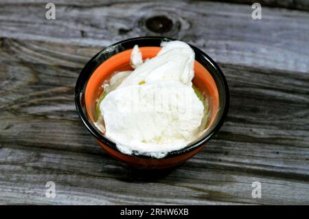 Gekühlte und gefrorene Eislöffel aus Vanille in einer Schüssel auf Holzuntergrund, bereit zum Servieren, weiße Eiskugeln auf einem Teller, Sel Stockfoto