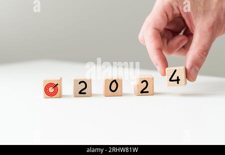 Planungsidee für das neue Jahr 2024, Holzblock-Würfel auf Holztisch mit Neujahr 2024 und Zielsymbol, Geschäftsvision. Stockfoto