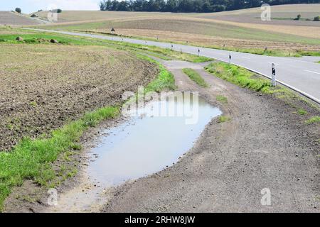 Wasserpfütze auf einer unbefestigten Straße Stockfoto