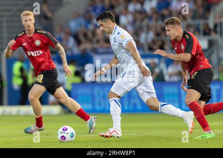 18. August 2023, Hessen, Wiesbaden: Fußball: 2. Bundesliga, SV Wehen Wiesbaden - Karlsruher SC, Spieltag 3, BRITA-Arena. Lars Stindl (Karlsruher SC, 13) wird von Florian Carstens (SV Wehen Wiesbaden, 17) verfolgt. Bjarke Jacobsen (SV Wehen Wiesbaden, 19) im Hintergrund links. Foto: Jürgen Kessler/dpa - WICHTIGER HINWEIS: Gemäß den Anforderungen der DFL Deutsche Fußball Liga und des DFB Deutscher Fußball-Bund ist es verboten, im Stadion und/oder im Spiel aufgenommene Fotos in Form von Sequenzbildern und/oder videoähnlichen Fotoserien zu verwenden oder zu verwenden. Stockfoto