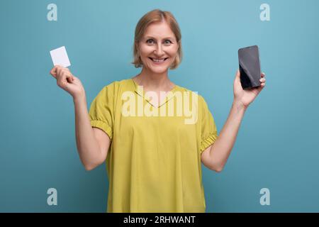 Eine blonde 50s-Frau kauft online mit ihrer Geldkarte Stockfoto