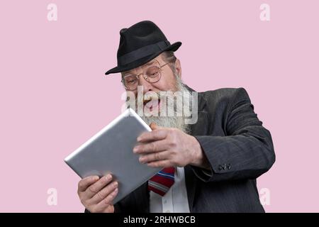 Porträt eines lachenden älteren Mannes mit Tablet-pc. Glücklicher Opa mit modernem Gadget. Isoliert n rosa. Stockfoto