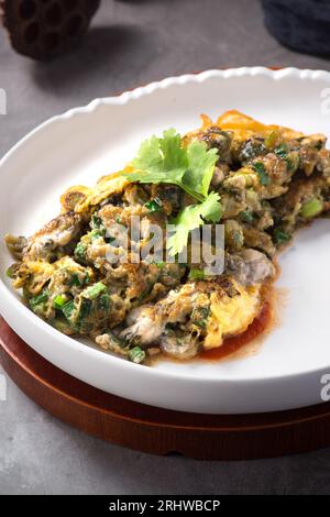 Chinesisches Austernomelett in heißer Pfanne, Krabben, chinesisches Essen. Knuspriger frittierter Austernpfannkuchen Stockfoto